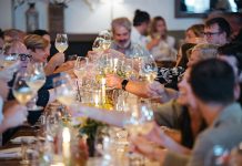 A group of people sitting at a table and raising their wine glasses for a toast.
