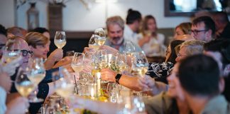 A group of people sitting at a table and raising their wine glasses for a toast.