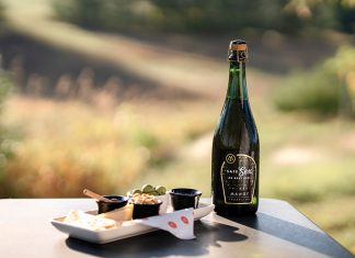 The Rise of Nonalcoholic Wine: A Passing Trend or New Frontier for Michigan Winemakers? A bottle of Mawby's Safe Sex NA Brut Rose with a plate of snacks.